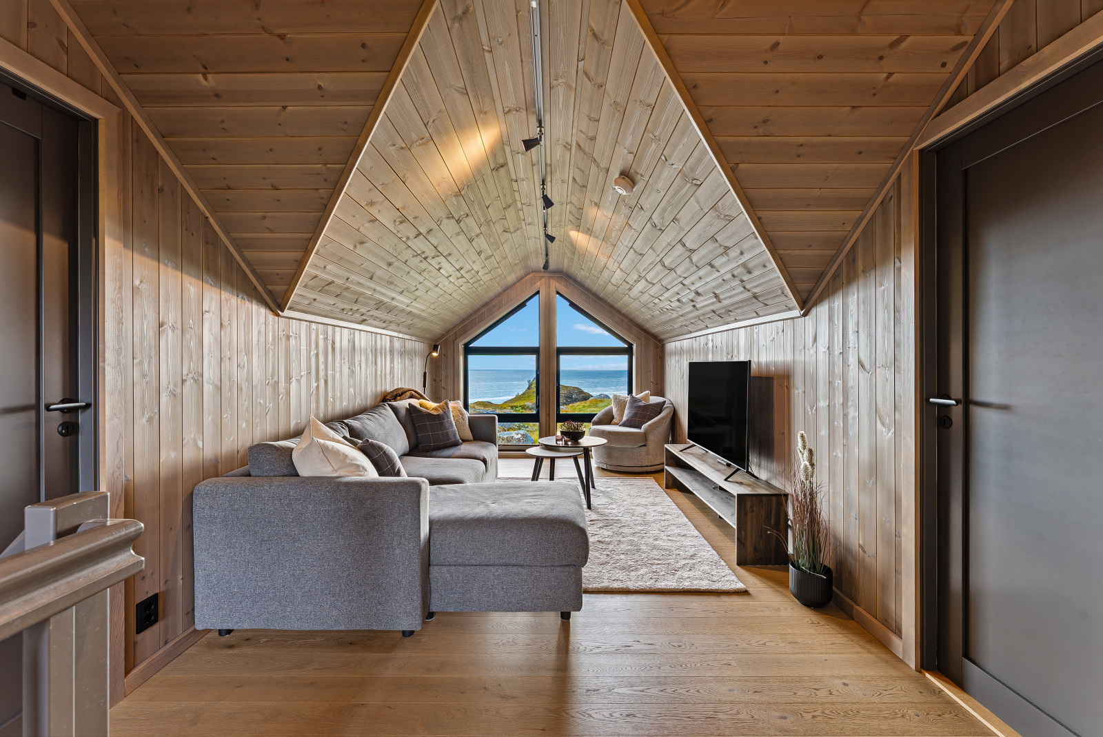 Loftstue med sofa, TV og utsikt mot havet