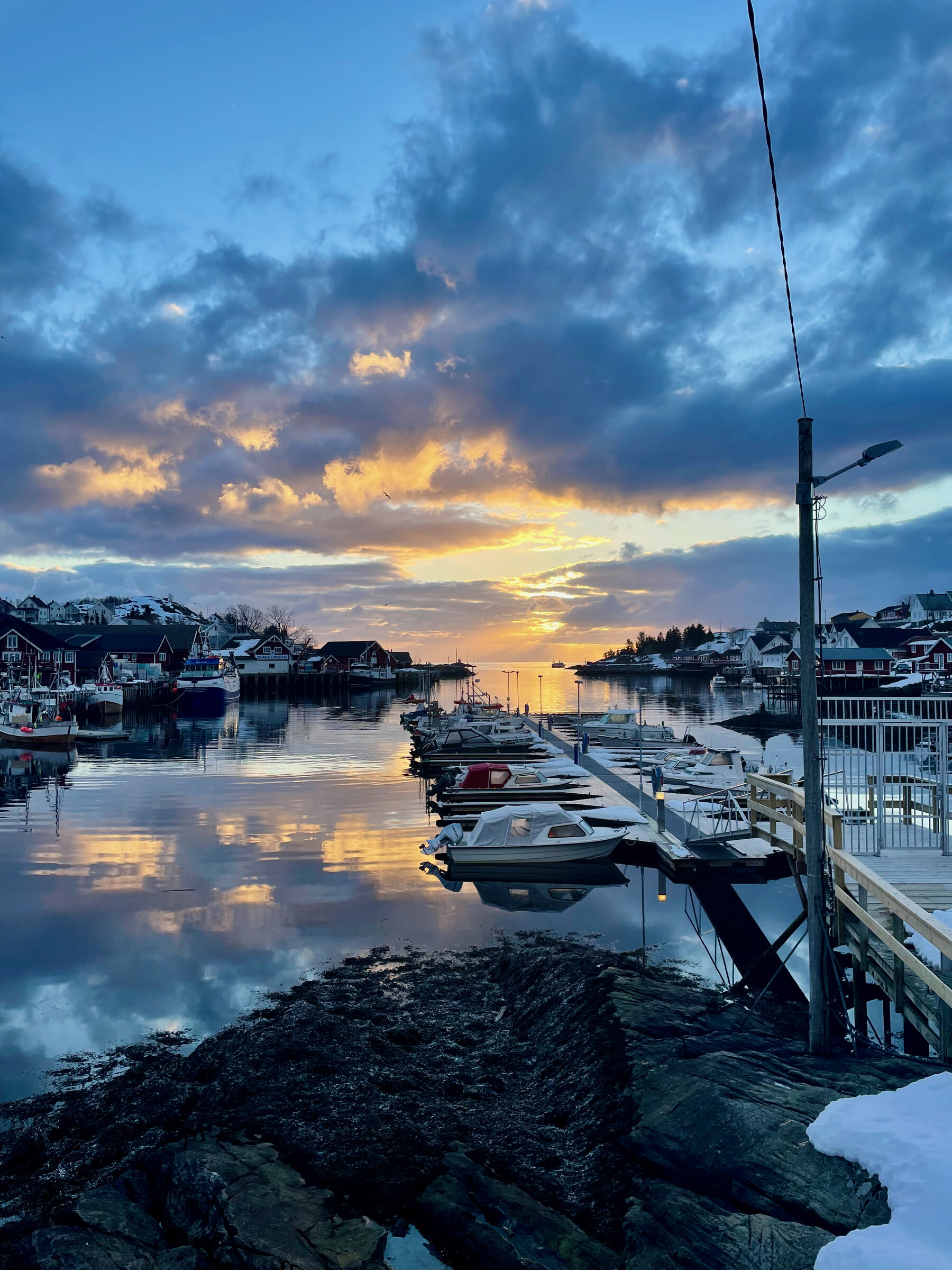 Vågen en stille vårkveld, med båter ved bryggen og solnedgang